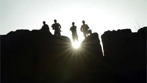 Getty Images Government soldiers stand guard in Ghor province