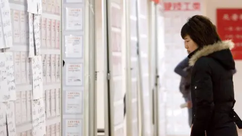 Getty Images A job-seeker looks at employment ads on billboards in Tiantian job fair in Shanghai, China.