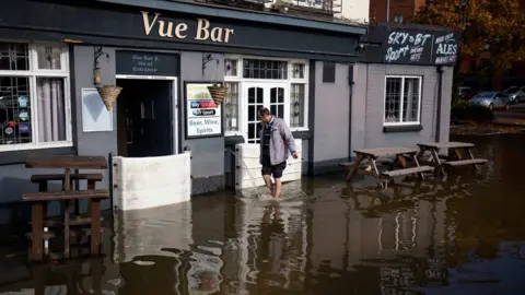 PA Media A staff member at the Vue Bar in Worcester installs flood defences