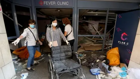 Reuters A woman wearing a face mask pushes a wheelchair at a damaged hospital following Tuesday"s blast in Beirut Lebanon August 5, 2020.