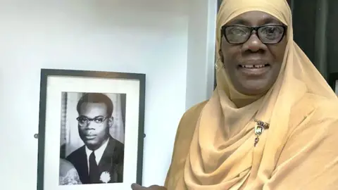 Kelso Cochrane's daughter Josephine stands in front of a portrait of her father