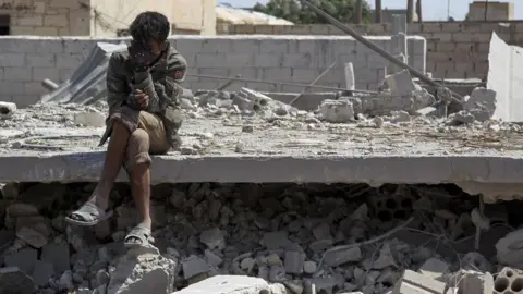 AFP A Syrian man sits amid the rubble of a building destroyed in a reported government air strike in Saraqeb, Idlib province (7 May 2019)