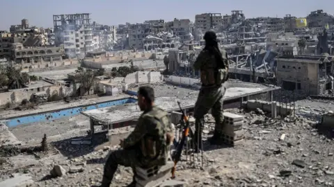 Getty Images Fighters of the Syrian Democratic Forces stand guard on a rooftop in Raqqa after retaking the city from Islamic State