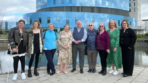 Nikki Fox/BBC Prof John Wallwork (centre) met with staff and former patients