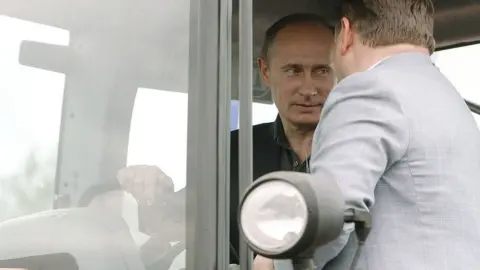 AFP Russia's Prime Minister Vladimir Putin (L) sits in the cabin of a tractor during his visit to the city of Tambov, some 480 km (298 miles) south of Moscow on July 2, 2010.