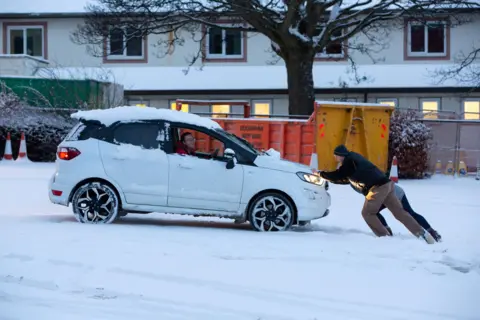 Pako Mera / Shutterstock People push a car trapped in snow