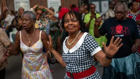 Getty Images People dance at the celebrations of the 75th anniversary of the arrival HMT Empire Windrush on June 22, 2023 in Tilbury, England