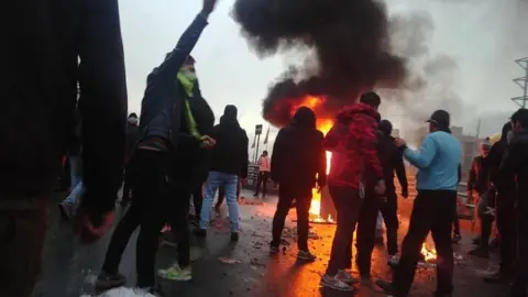 AFP Iranian protesters gather around a fire during a demonstration against an increase in petrol prices in Tehran (16 November 2019)