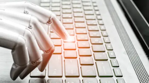 Getty Images A robot hand writing on a keyboard