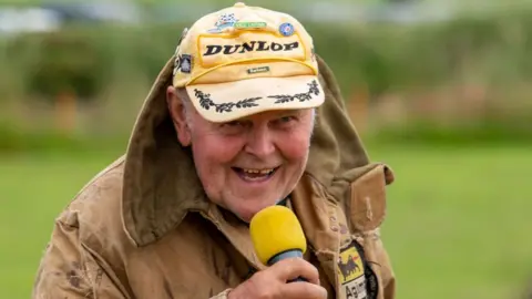 Islephoto.co.uk Derry Kissack holding a microphone