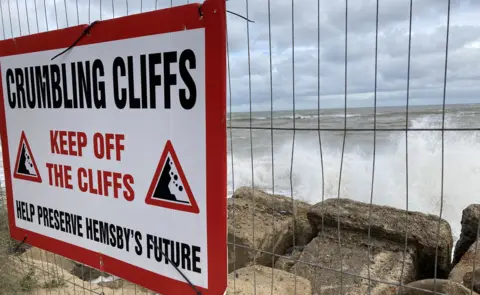 Jenny Kirk/BBC A warning sign telling people to keep off the cliffs at Hemsby, Norfolk