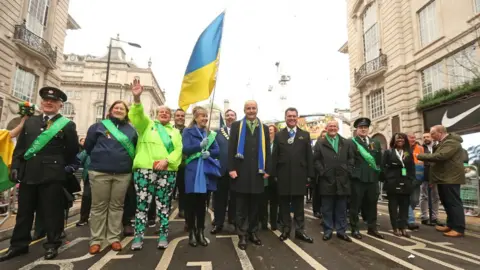 James Manning/PA Wire Taoiseach Micheal Martin (centre) with Natalia Lesyuk from the Ukraine (centre left with flag) during the St Patrick"s Day parade in London