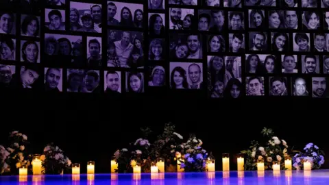 Reuters Candles are lit in front of the photos of the victims of the downing of Ukraine International Airlines flight PS752, in Toronto, Canada (8 January 2023)