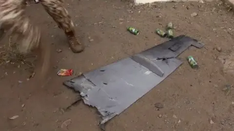 AFP Screengrab taken from video showing Yemeni soldier walking past the wing of a drone that exploded above al-Anad military base in Lahj, Yemen (10 January 2019)