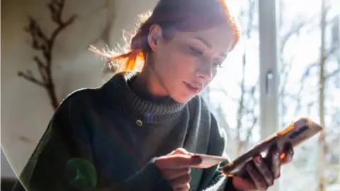 Woman looking at mobile phone and credit card