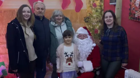 Iryna Mezenina A little girl pictured with her mother, aunt, grandmother, grandfather and Santa