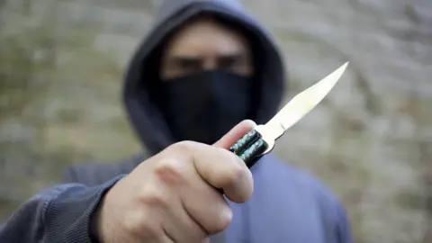 Getty Images A hooded youth brandishes a knife