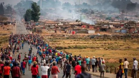 Getty Images A mob armed with spears, batons and axes run through Johannesburg's Katlehong Township during a new wave of anti-foreigner violence on September 5, 2019