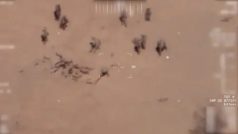FRENCH ARMY Screengrab of drone footage showing two people throwing sand over the bodies