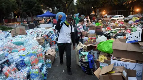 AFP A man walks through piles of food and water bottles