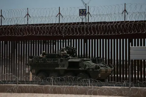 Getty Images A US armored vehicle at border near El Paso with fence and barbed wire behind the tank.