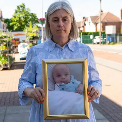 BBC/Chris Waring Michelle Welsh holds a framed picture of her son