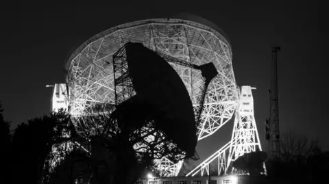 Getty The Mark II telescope seen illuminated at night behind the Lovell Radio Telescope at Jodrell Bank Observatory.