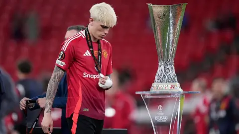 Alejandro Garnacho walks past the Europa League trophy