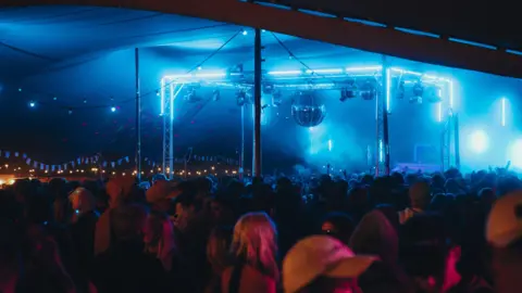 Matt Greenwell People gather under large disco balls at one of the dance stages. 