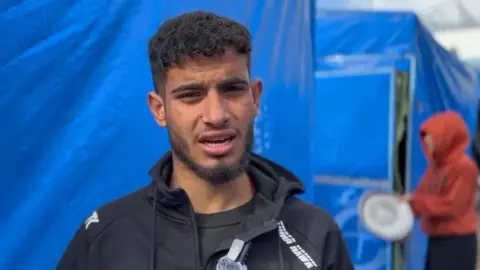 BBC Displaced Palestinian Mahmoud Bahjat speaks to the BBC at a tent camp in Deir al-Balah, central Gaza (5 February 2025)