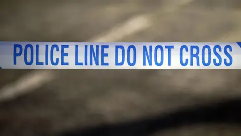 Police line do not cross written in blue across white tape