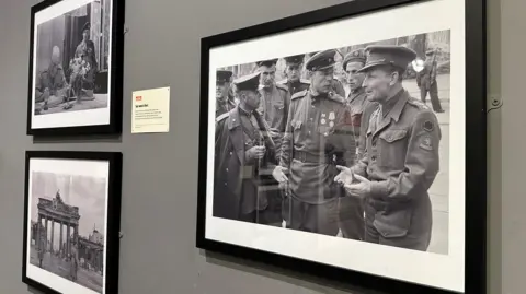 LEONARD MCCOMBE There framed photos on a wall with the largest featuring British and Russian soldiers in conversation.