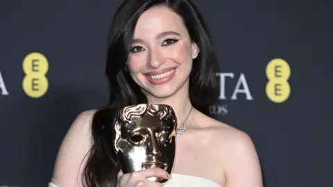 Getty Images Mikey Madison smiling and holding her Bafta