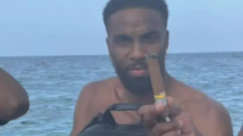 Nottinghamshire Police James is holding a large cigar with the sea behind him