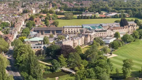 An aerial view of Magdalen College School, which is a mixture of new and old buildings next to a large green space and a river.