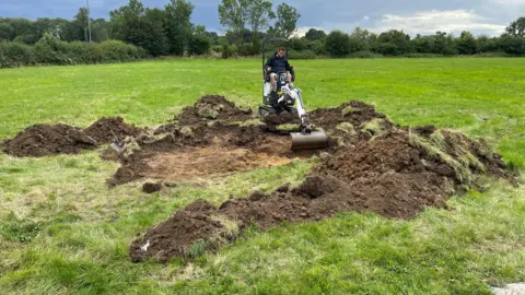 David Dunn A man sat on a digger with piles of soil in front