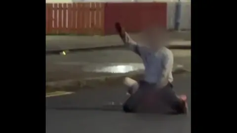 A image of a man with his hand up in the air. His face is blurred. 