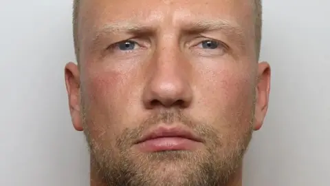 Mugshot of man with short hair and beard