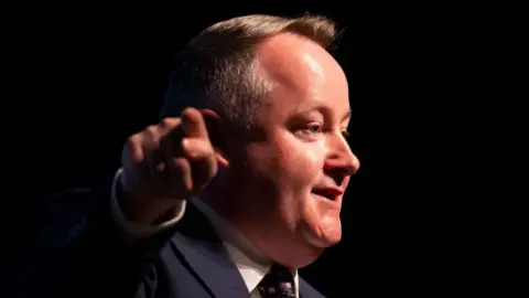 Getty Images Welsh Conservative Senedd group leader Darren Millar smiling and looking away from the camera. His finger is pointing towards the camera