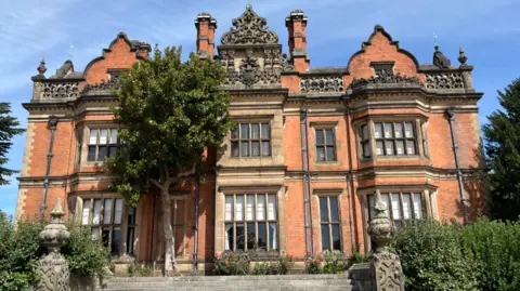 A large red brick mansion in the sunshine