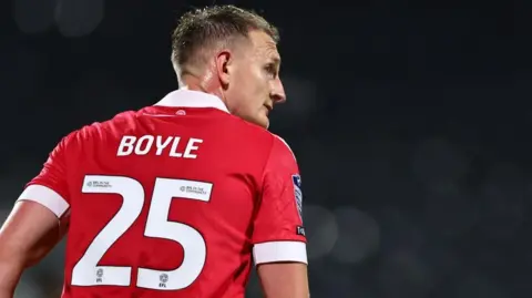 Wrexham defender Will Boyle with his back to the camera showing his surname and number 25 during a match