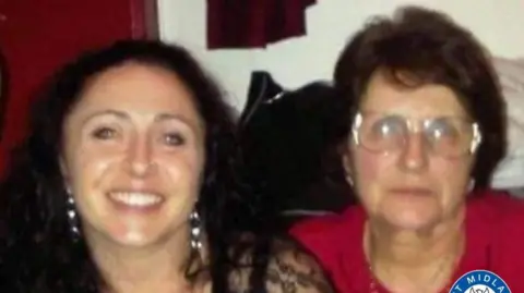 Handout Amanda Riley is pictured smiling, she has curly long black hair. she is sat next to Linda Philips who wears large round glasses and has short brown hair. She is wearing a red shirt.