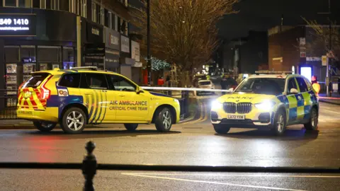 ASP An Air Ambulance car and police car are parked nose-to-nose in front of police tape 
