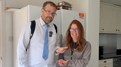 Simon Balch Simon Balch stands next to Jo Willis in a kitchen. In his open palm rests a spherical egg. Jo has both her hands resting slightly below Simon's. They are both looking at the camera and smiling. Simon has short dark hair, a beard, and wears glasses, a white shirt, blue tie, rucksack and has a small microphone attached to his shirt. Jo has long red hair, glasses, and wears a grey jumper with a dark T-shirt underneath. 