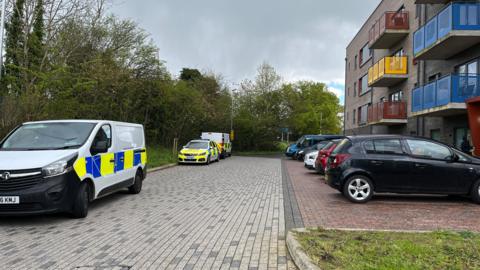 Police vehicles outside Juniper Square