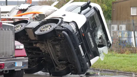 An overturned lorry is recovered. 