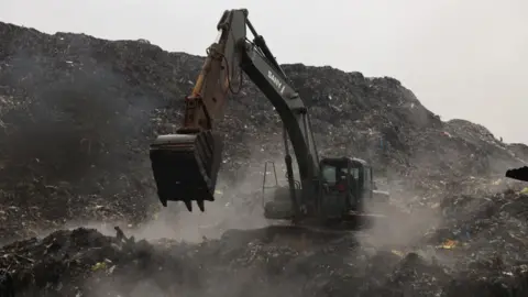 Reuters A digger is picking up rubbish amid the dump site.