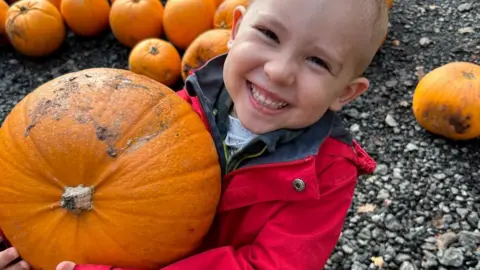 Harry, who was diagnosed with cancer when he was four, carries a pumpkin