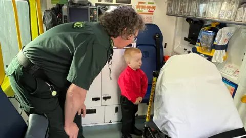 EMAS Richard being given a tour of an ambulance by one of the paramedics who helped his mother