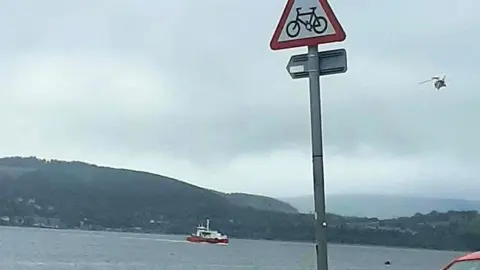 A ferry on the River Clyde as a search operation is launched for a person overboard. A helicopter can be seen in the sky above